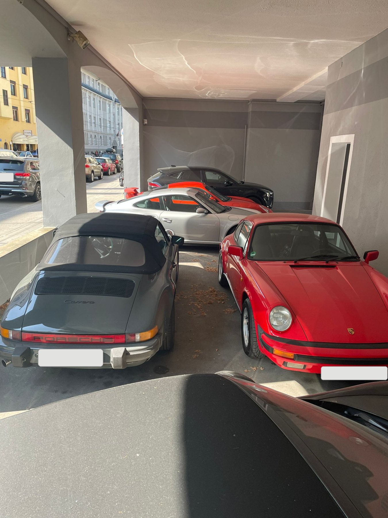 Zwei klassische Sportwagen in Grau und Rot unter dem Vordach