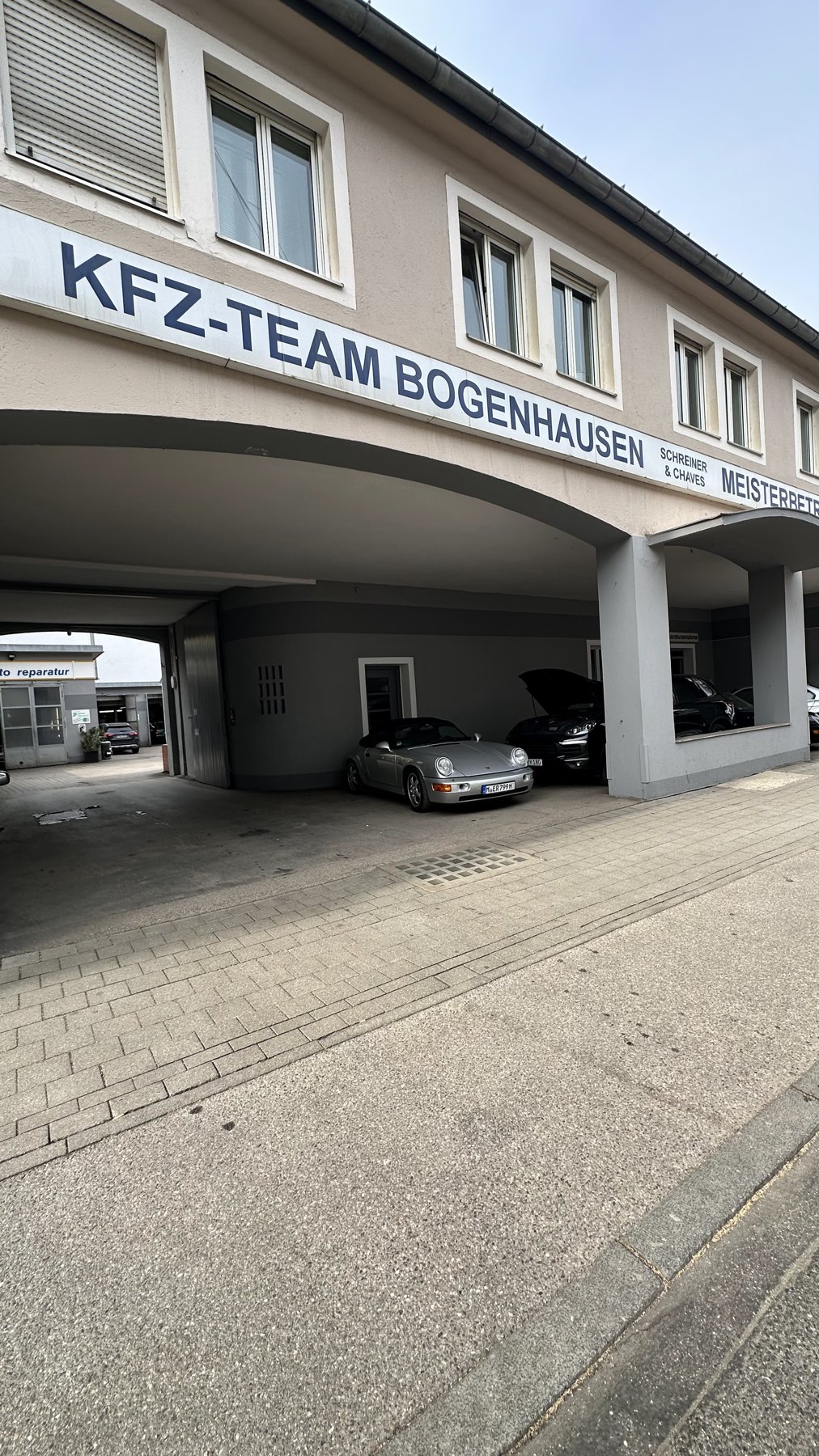 Hausfassade mit dem Schriftzug Kfz-Team Bogenhausen, Schreiner und Chaves, Meisterbetrieb, über der Durchfahrt